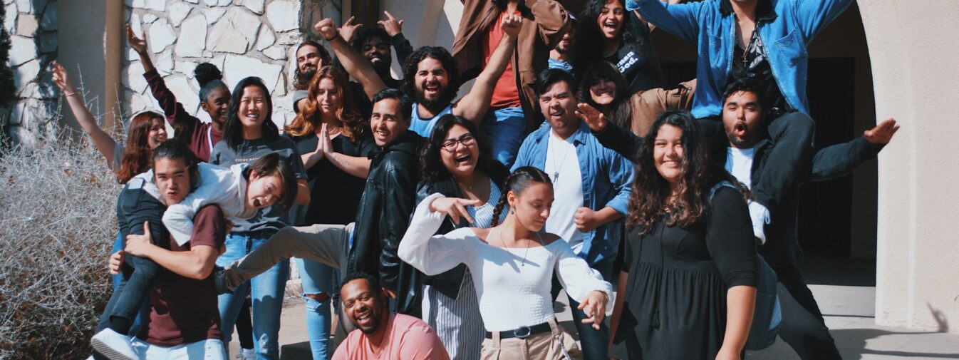 Group of people posing happily outside building.